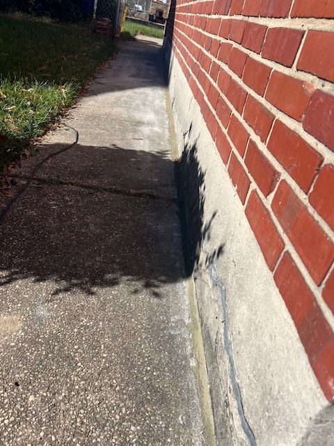 Sidewalk next to red brick building. Sunlight casts shadows on concrete.