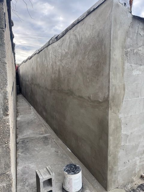 Narrow alley with newly plastered concrete walls; overcast sky.