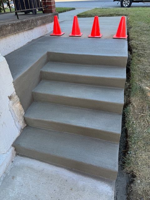 Freshly poured concrete steps with safety cones.