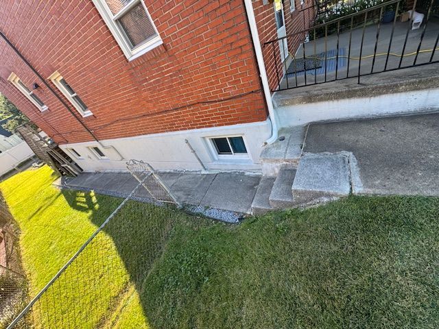 Brick building with concrete steps and a patch of grass.