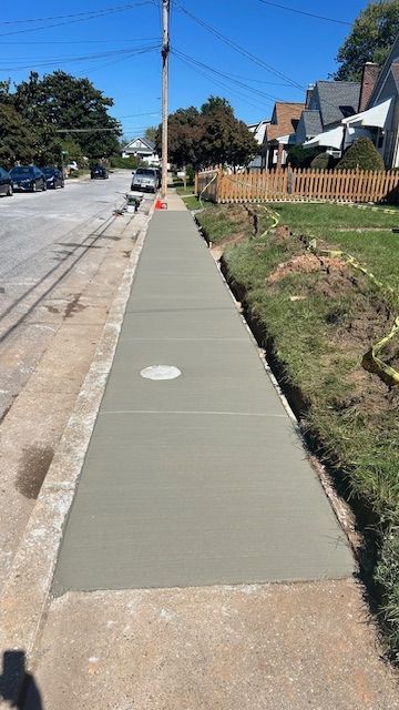 Freshly poured concrete sidewalk with a utility access cover.