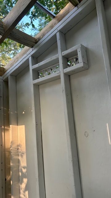 White-painted interior wall with framing. Small glass blocks are set in a framed opening.