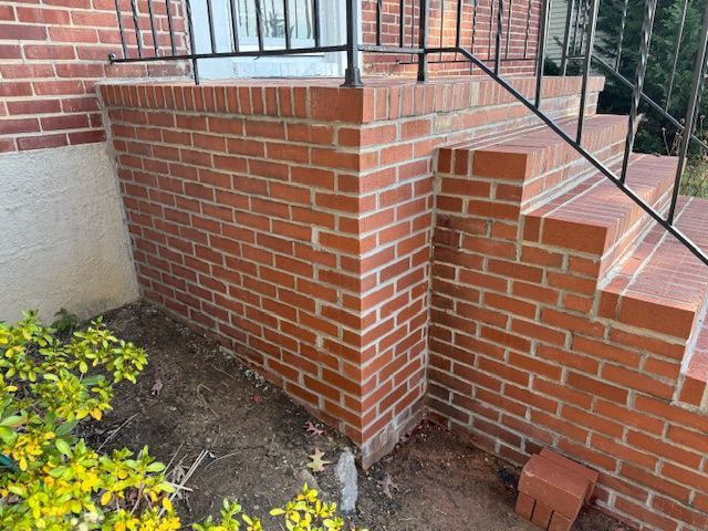 Red brick exterior steps leading to a building's entrance. Black railing is present.