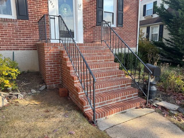 Brick front steps with black metal handrails leading to a house entrance.