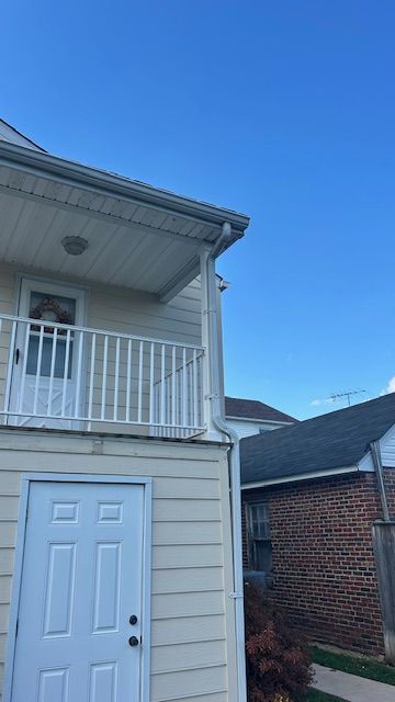Exterior view of a two-story building with a balcony, white door, and blue sky.