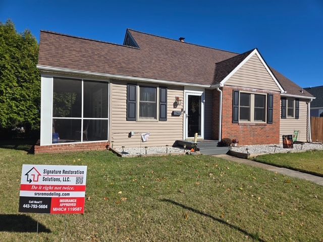 Tan house with brown roof and brick accents, in front yard, with sign: Sunrise Restoration Solutions, LLC.
