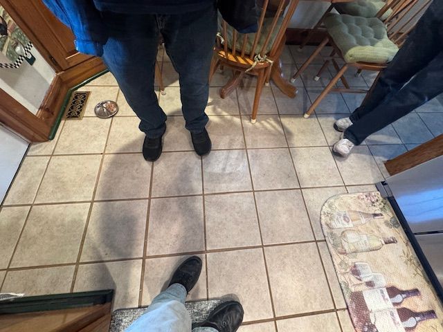 People standing on a tiled floor near a dining table.