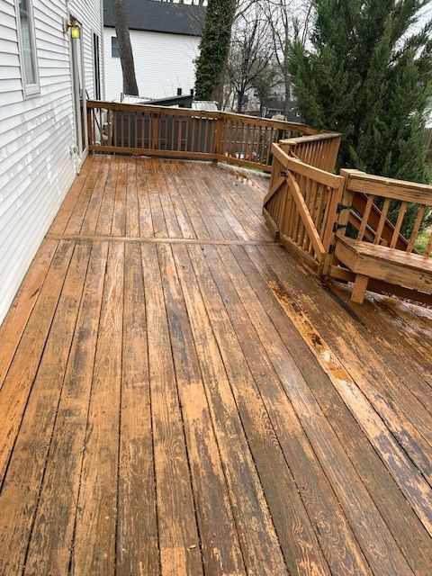 Wooden deck with peeling stain, railing, attached to a white building.