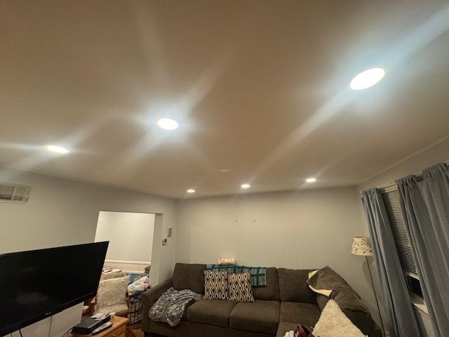 Living room with recessed lights, couch, TV, and doorway.