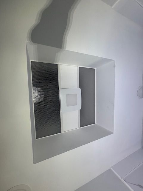 White ceiling vent with a sensor in the center and dark grates.