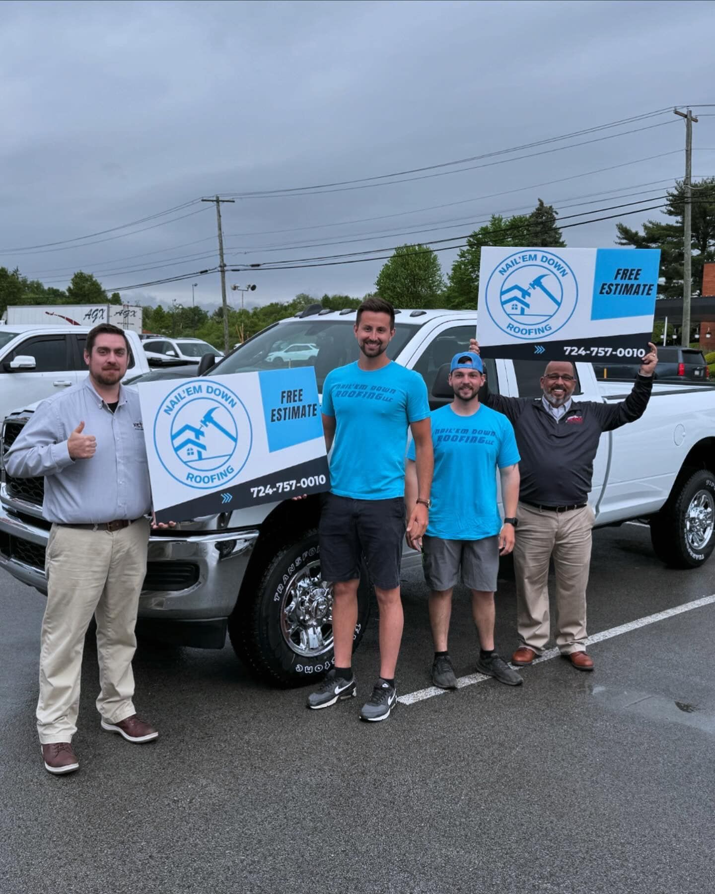 A group of men are standing in front of a truck holding signs.