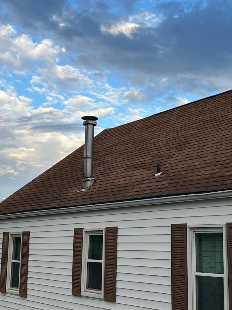 A white house with brown shutters and a brown roof.