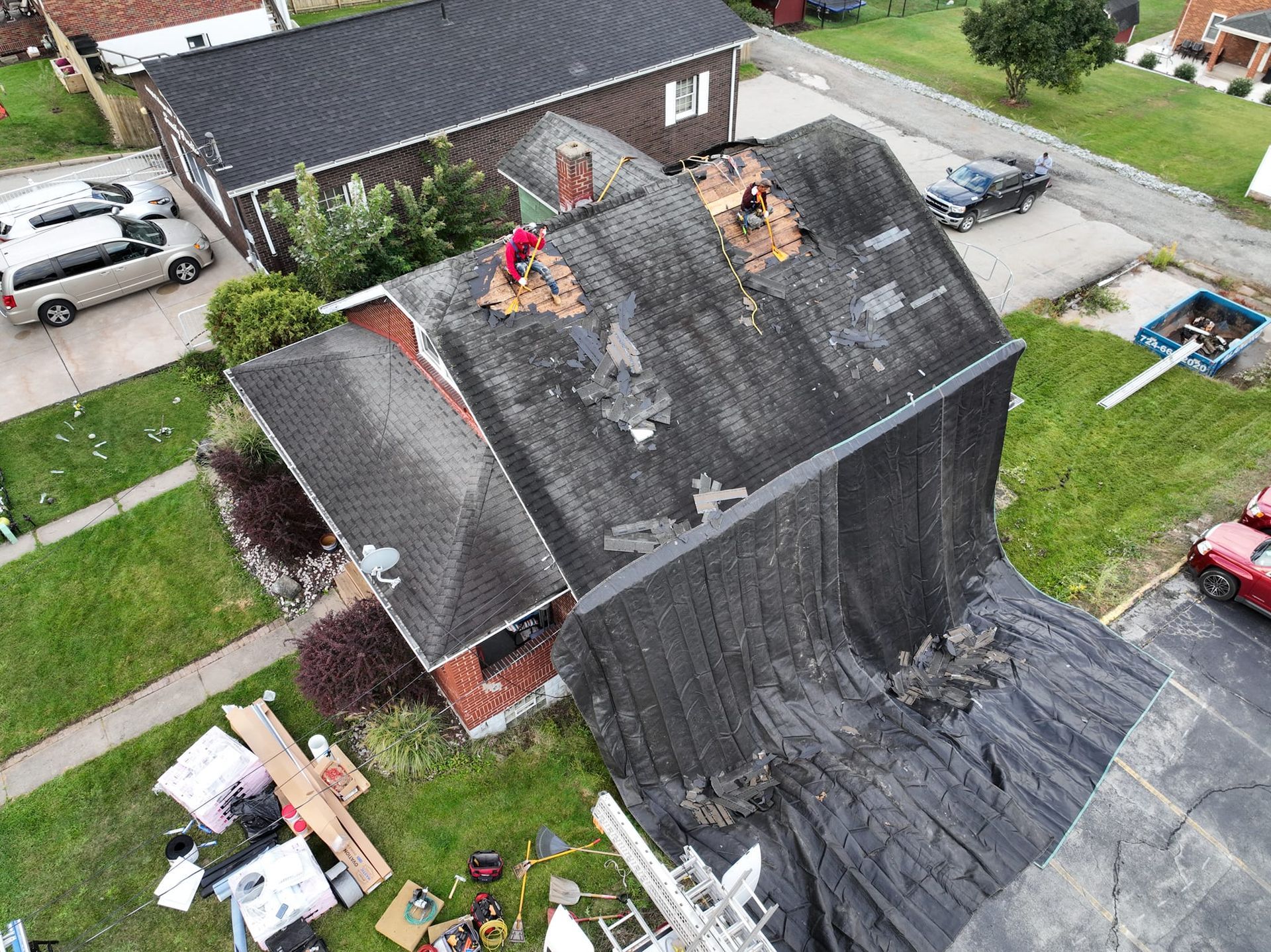 An aerial view of a roof being repaired in a residential area.