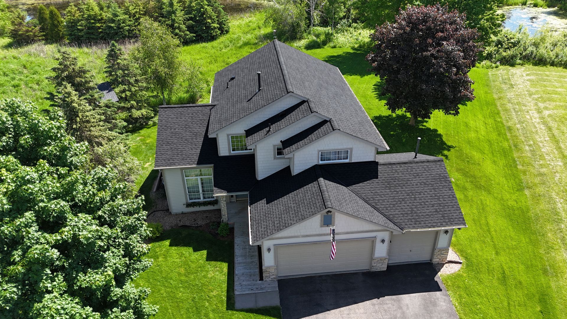 An aerial view of a house with a lot of trees in the background.