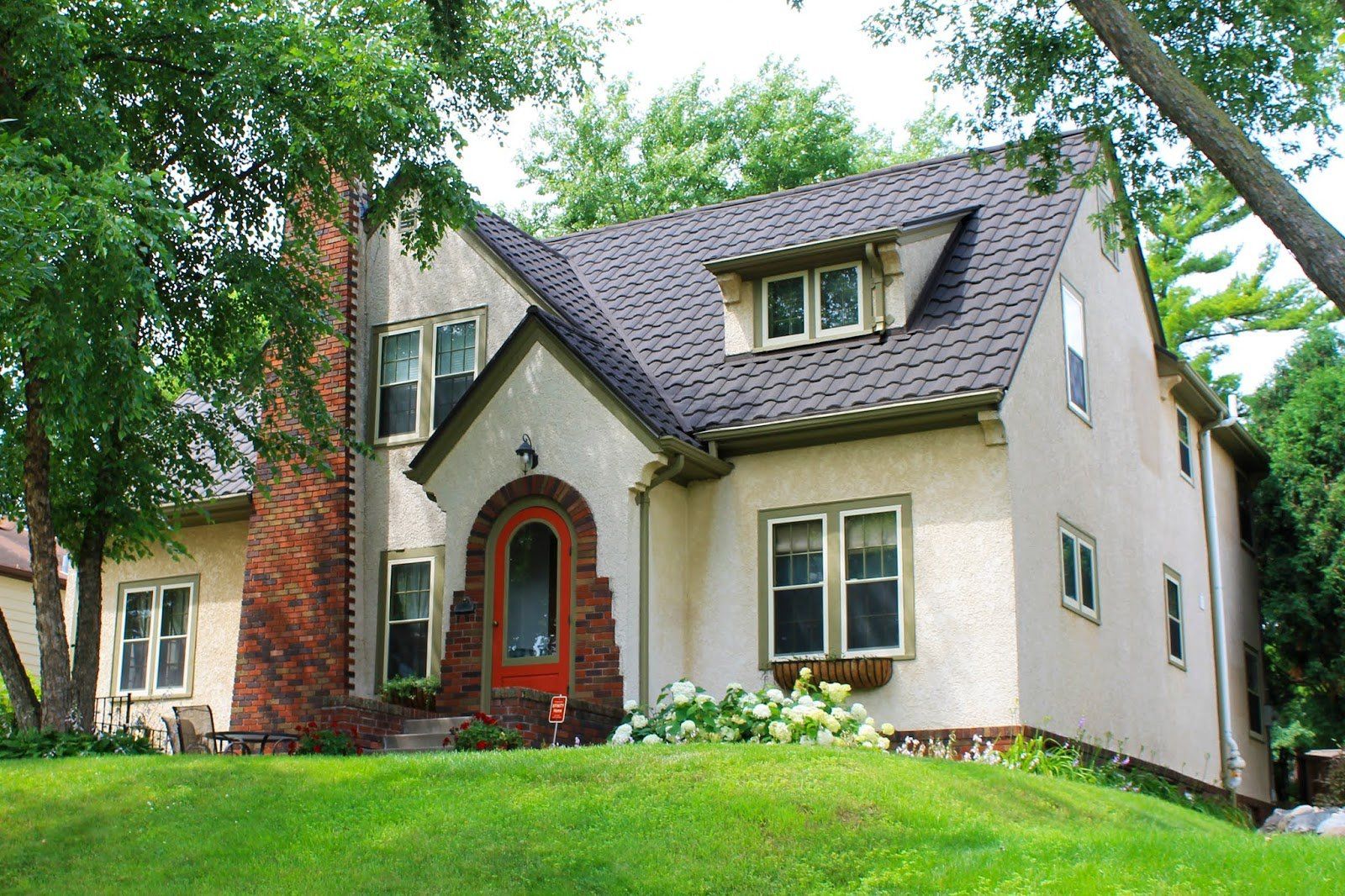 A white house with a brick chimney and a red door