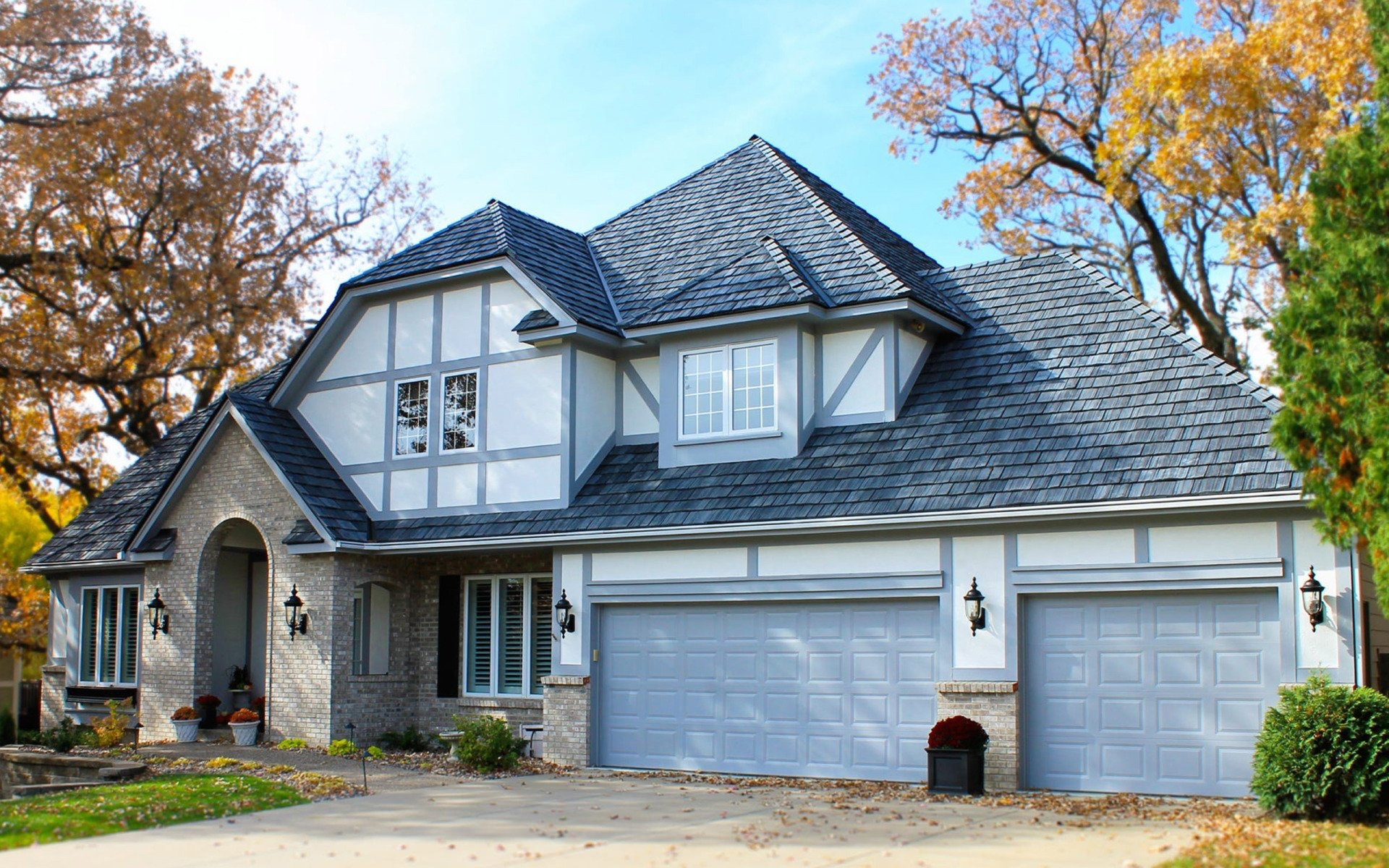 A large house with three garage doors and a gray roof.