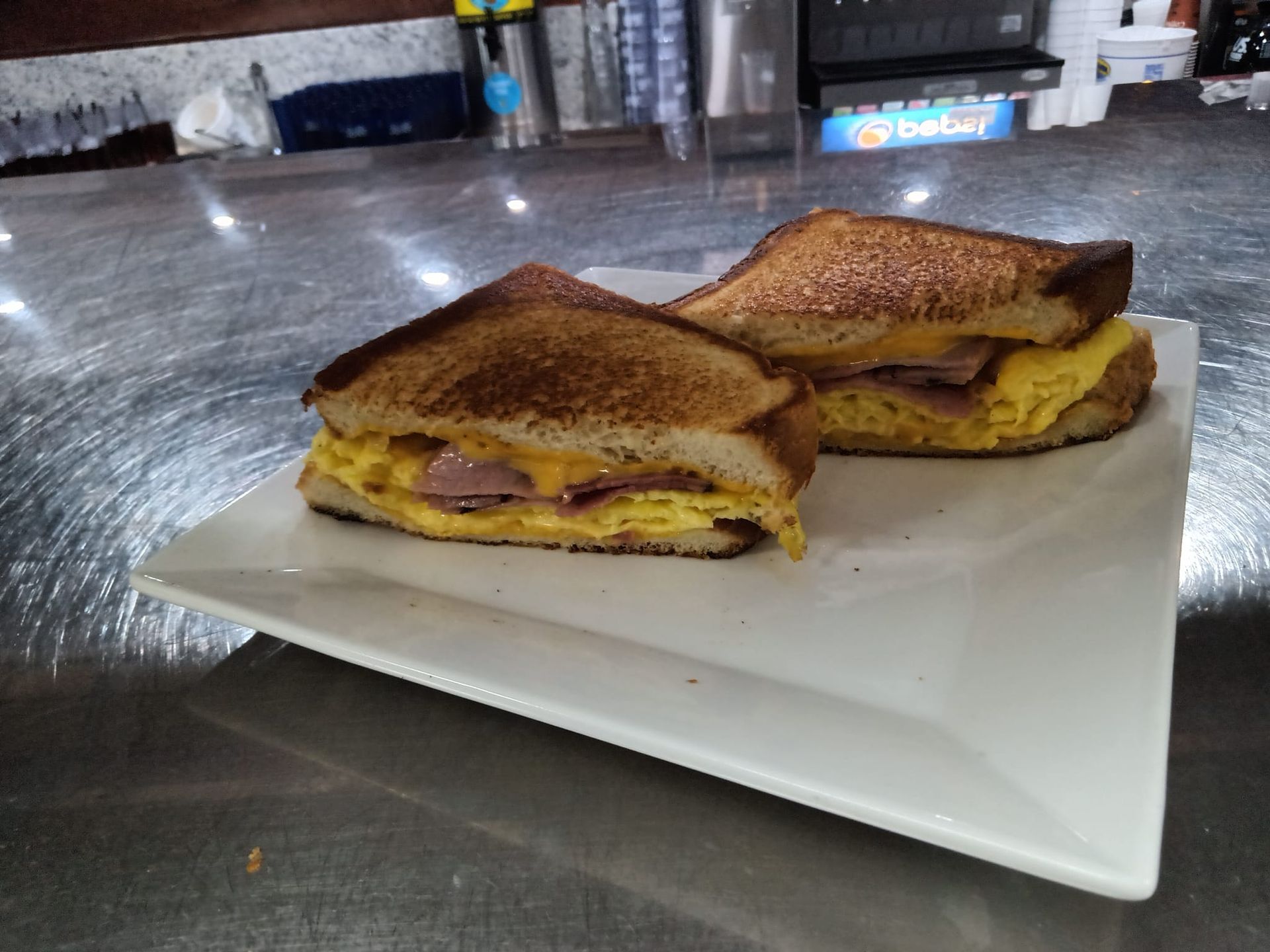 Two sandwiches are on a white plate on a counter.