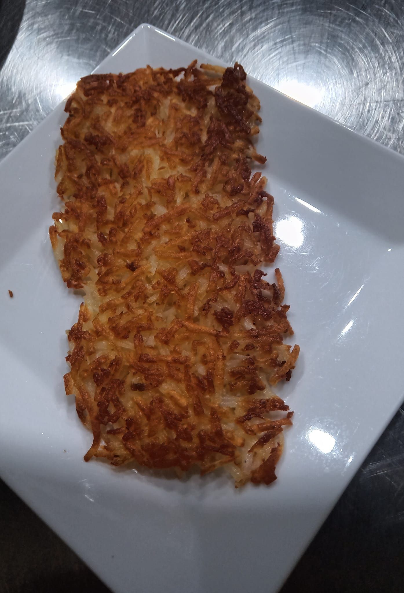 A white plate topped with a piece of fried food on a table.