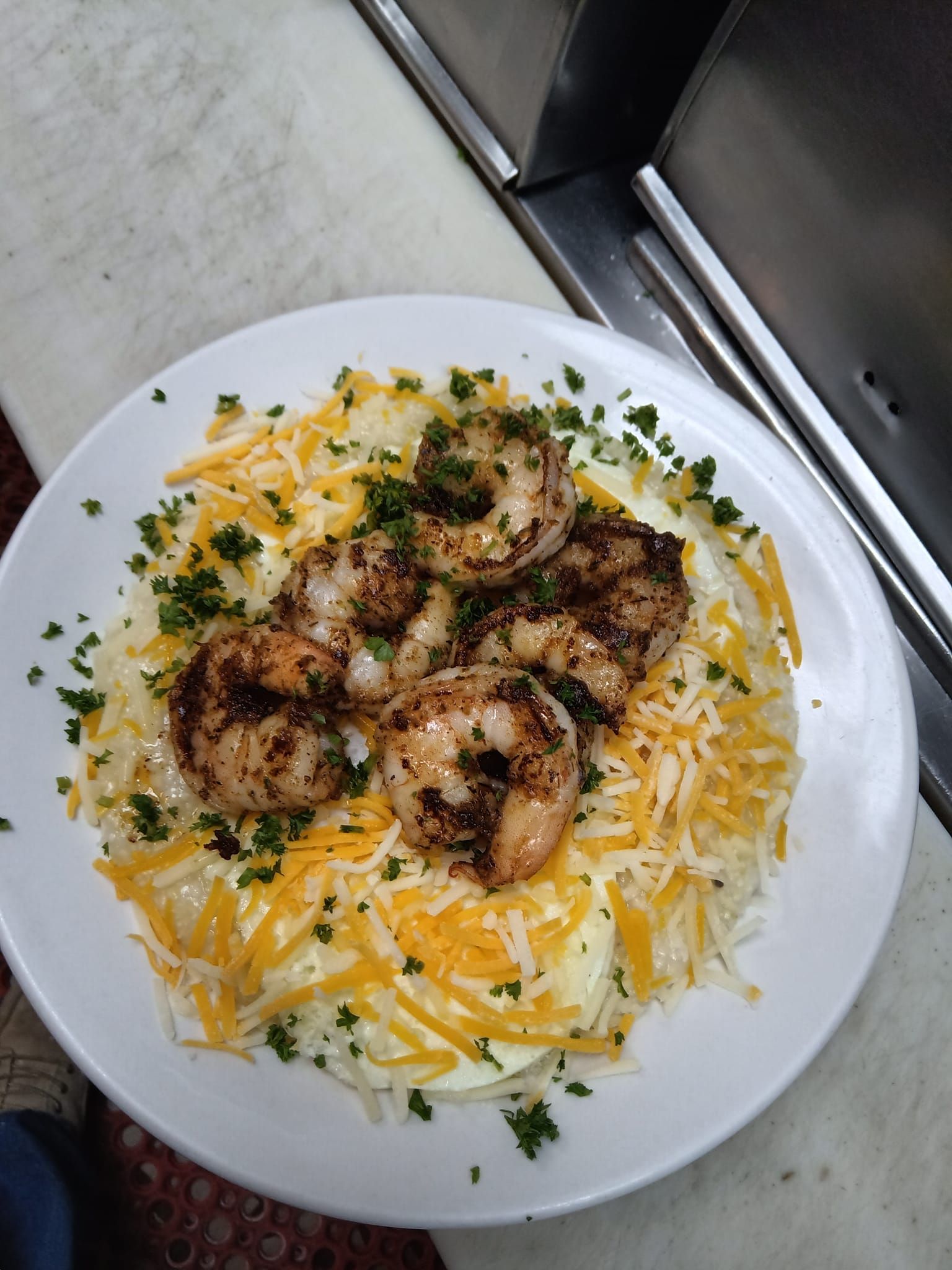 A white plate topped with shrimp and mashed potatoes