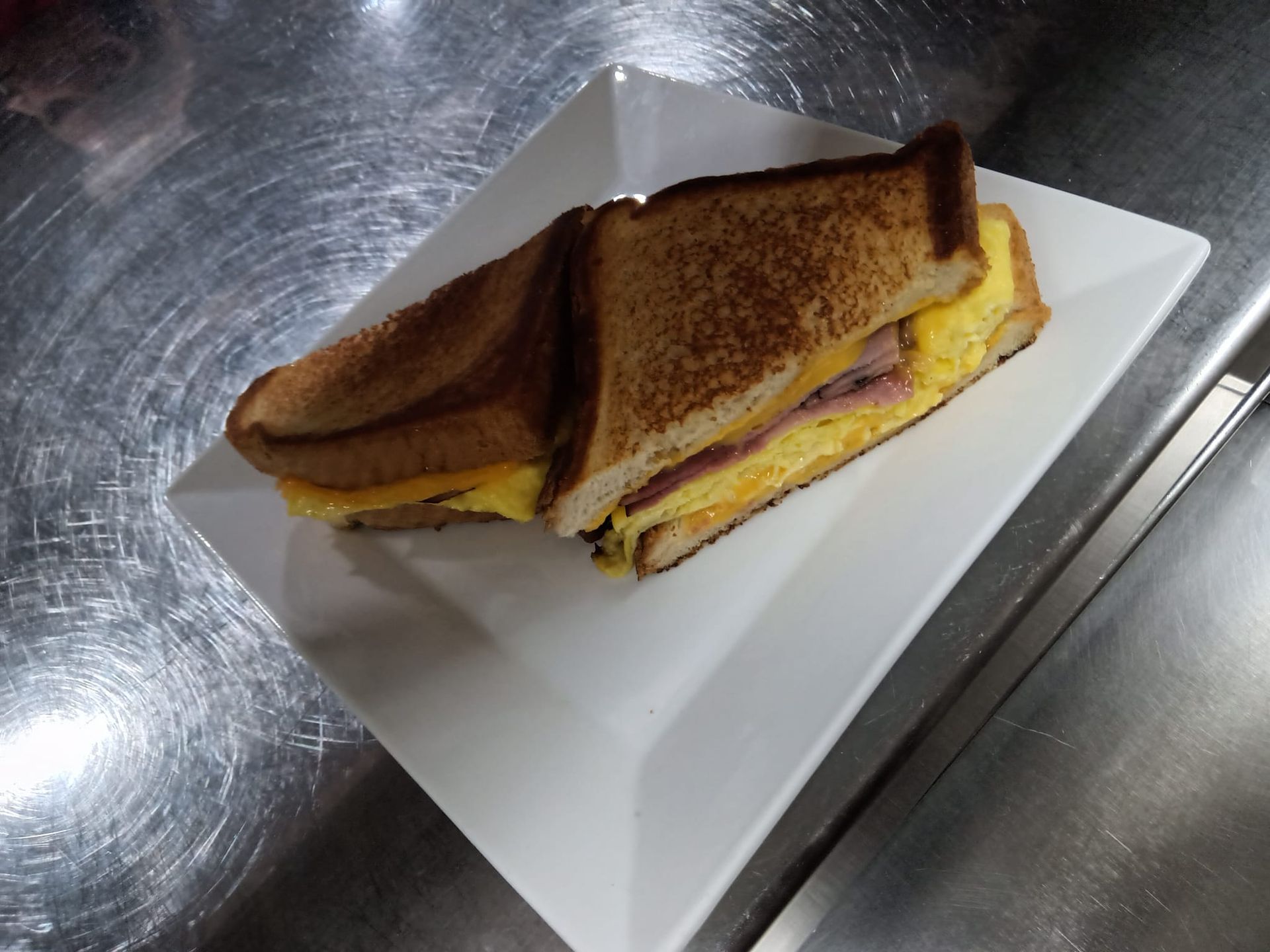 A grilled cheese sandwich is on a white plate on a counter.