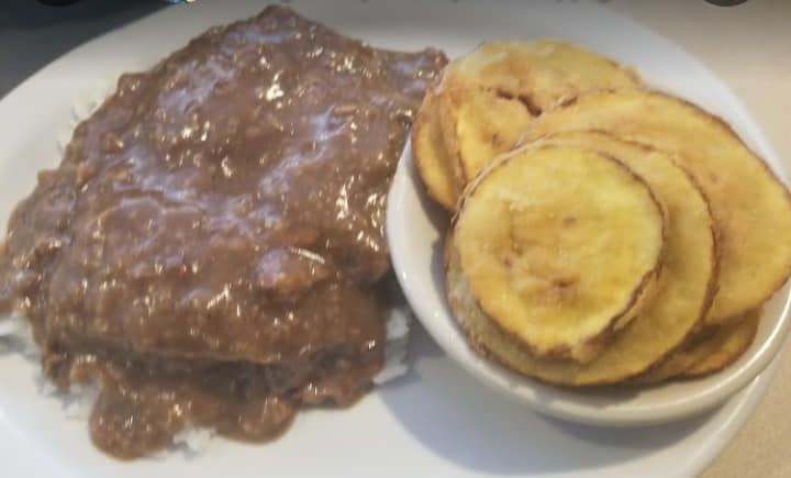 A plate of food with a bowl of fried potatoes on a table.
