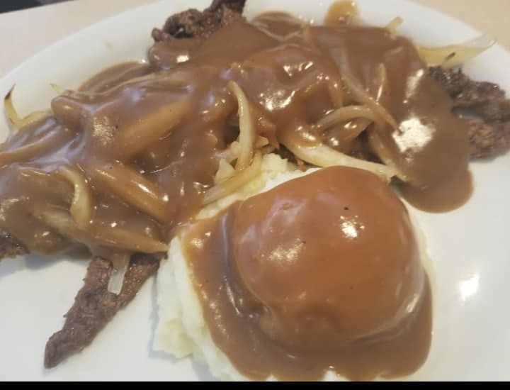 A close up of a plate of food with gravy and mashed potatoes