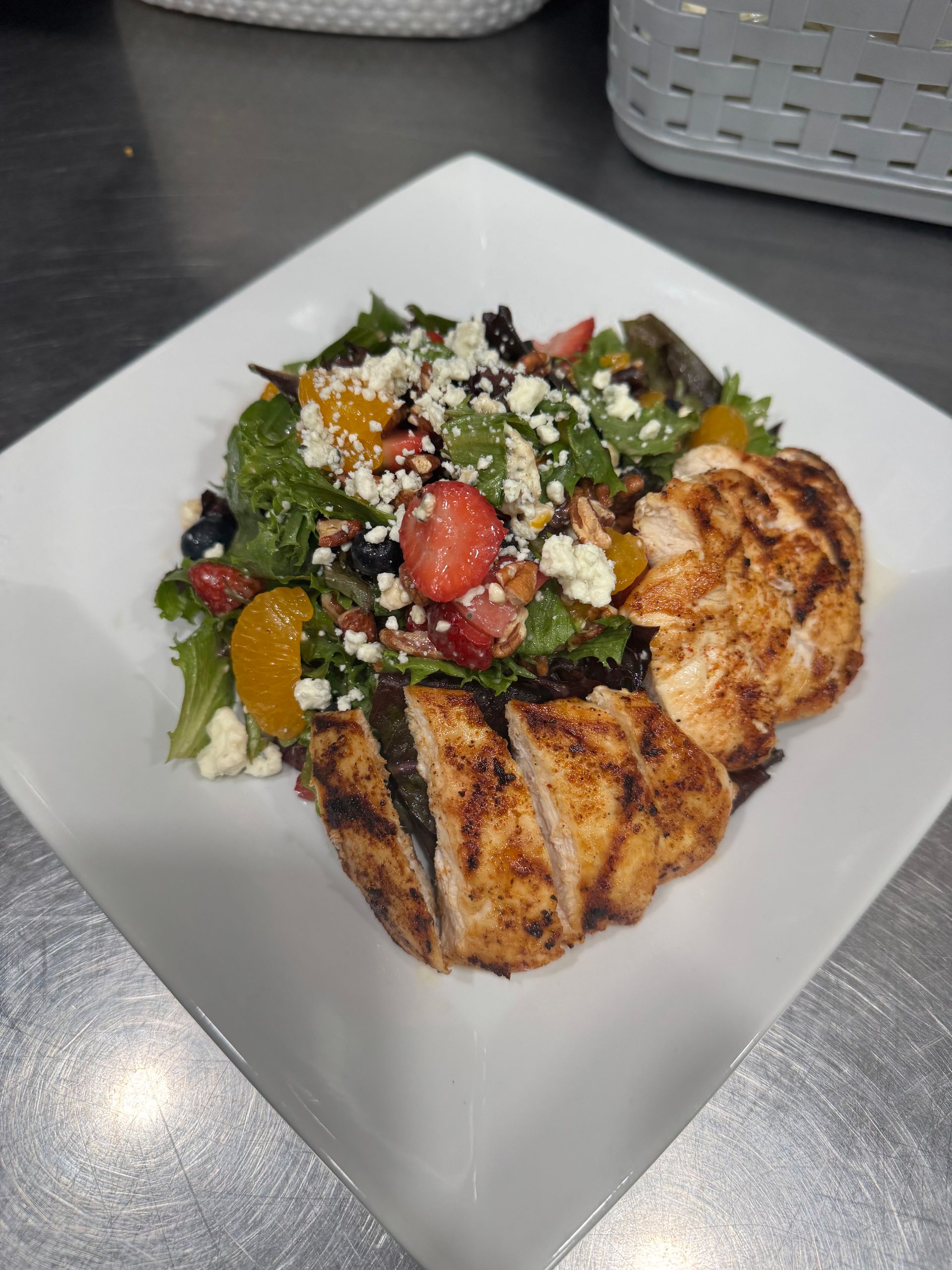 A white plate topped with a salad and chicken on a table.