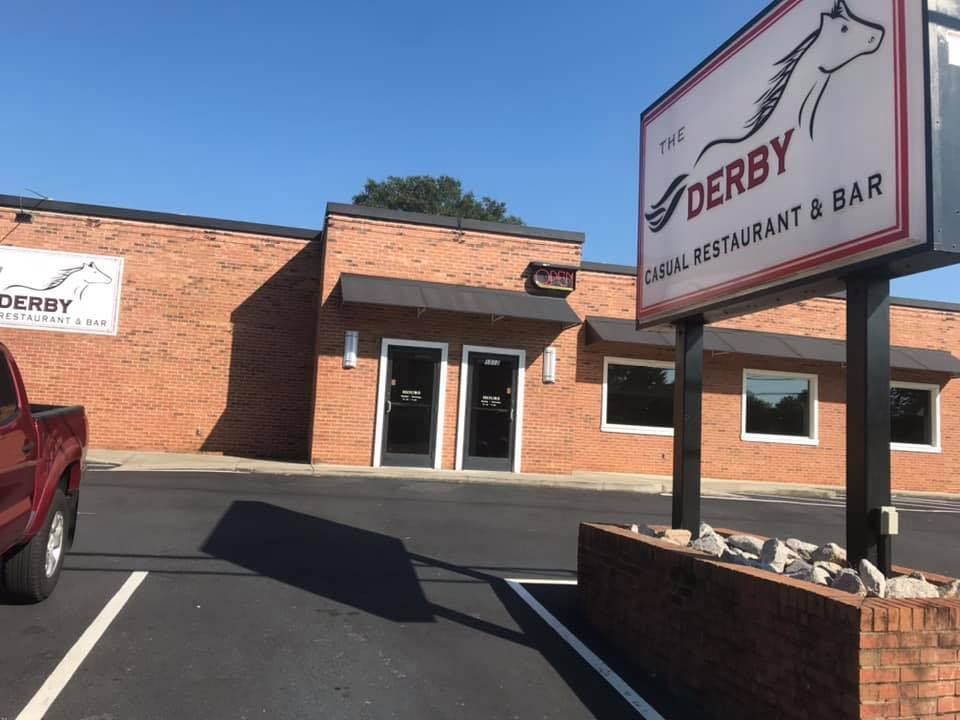 A red truck is parked in front of the derby restaurant and bar