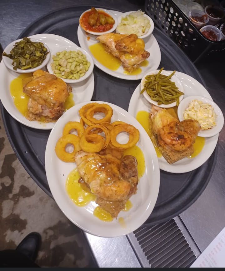 A tray filled with plates of food including chicken green beans and onion rings