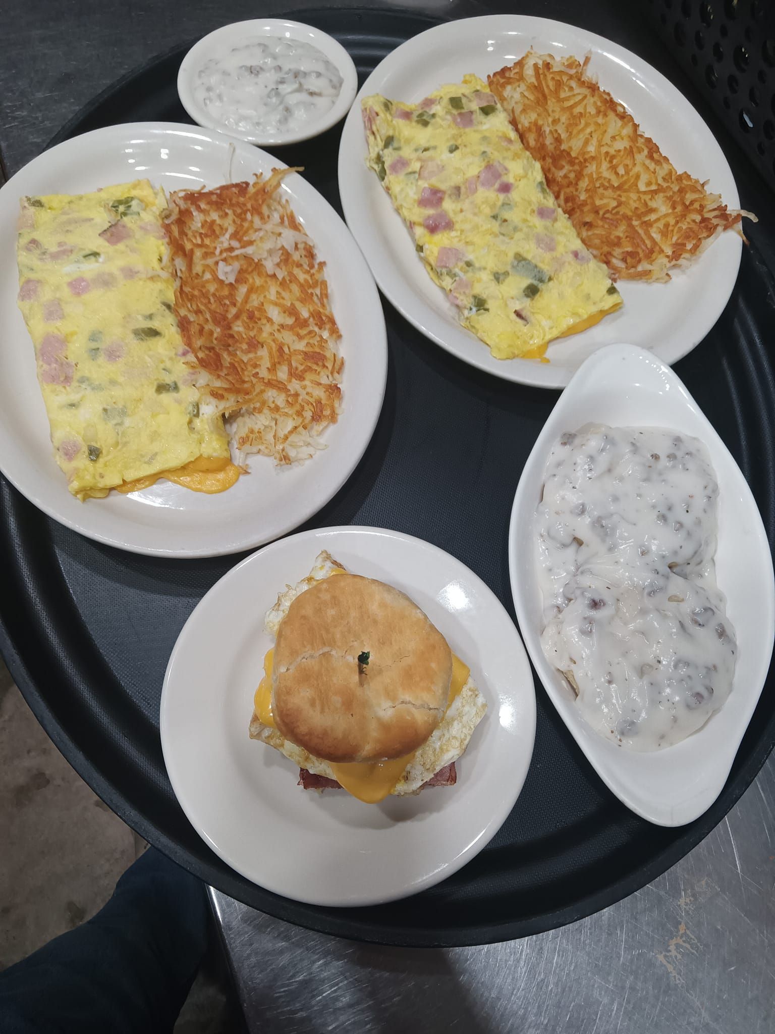A tray of food including eggs , hash browns , a sandwich and a biscuit