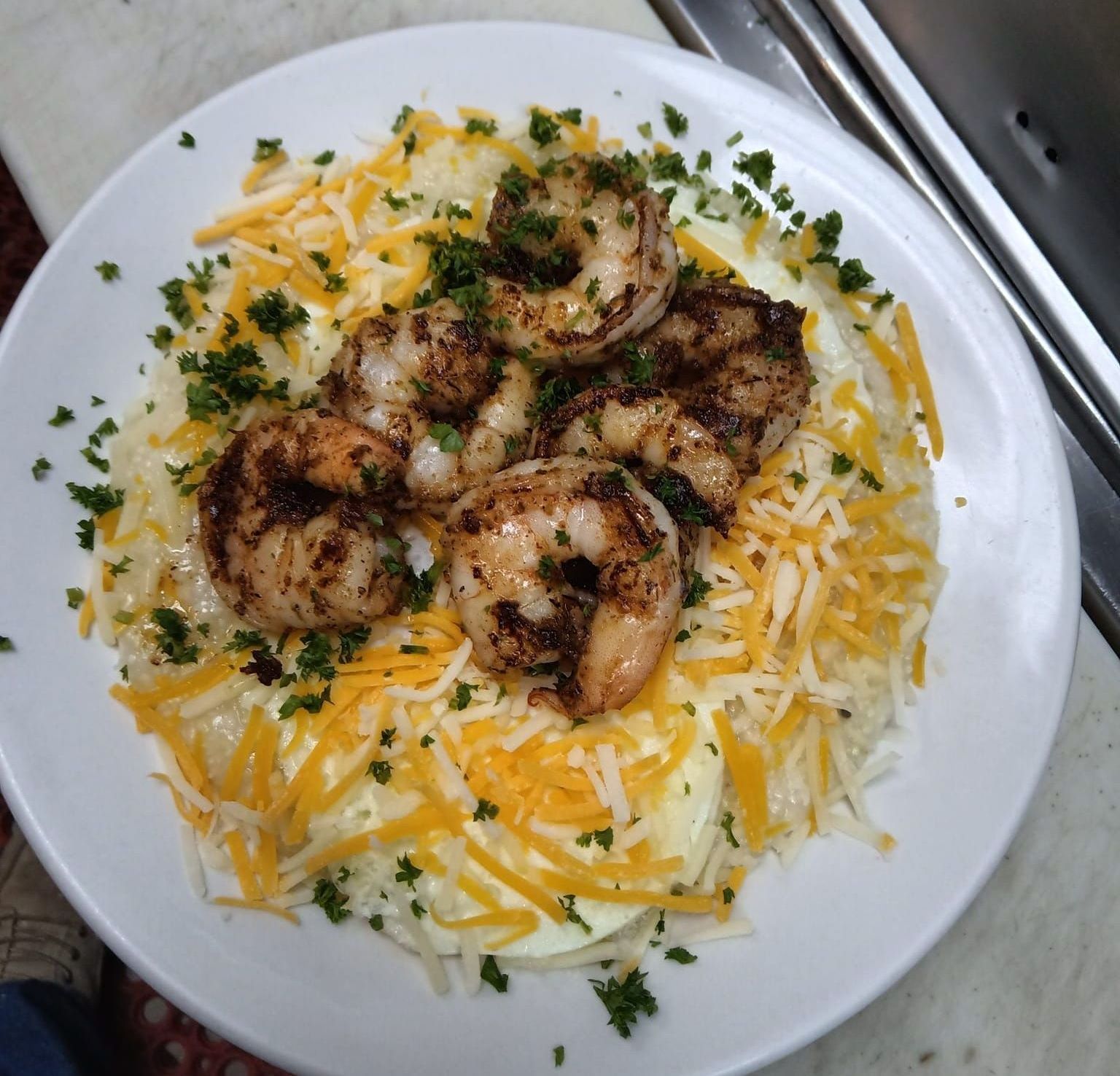 A white plate topped with shrimp and mashed potatoes