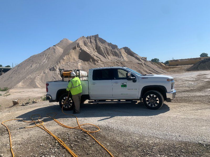 A white truck is parked in front of a pile of dirt.