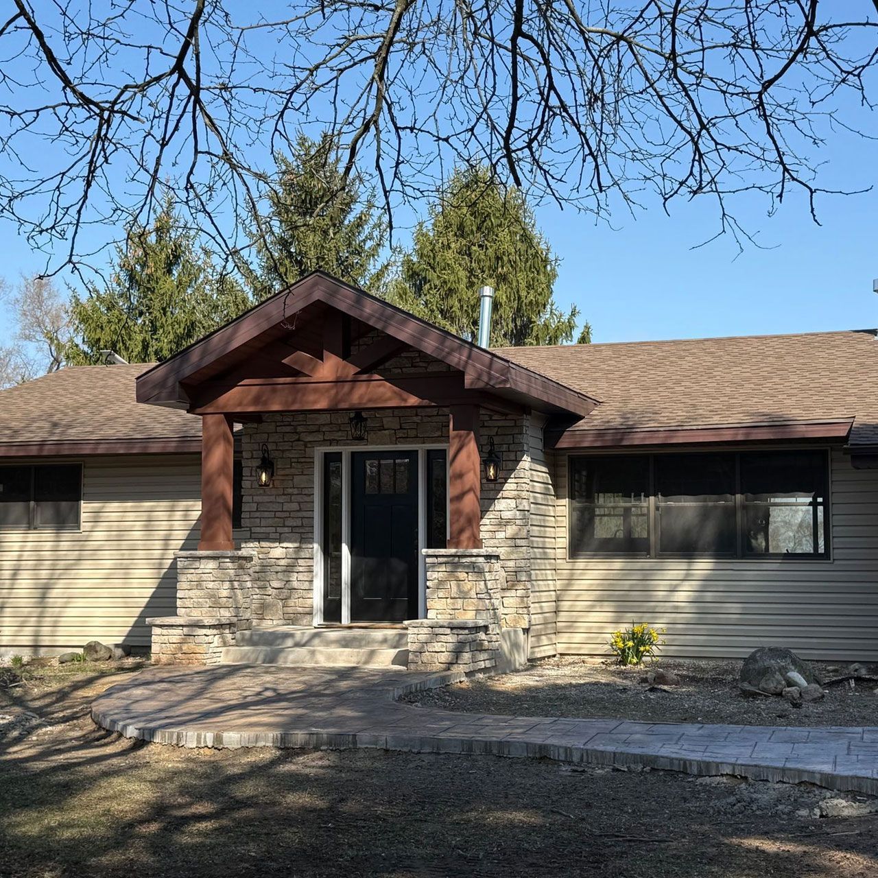 A house with a brown roof and a stone porch