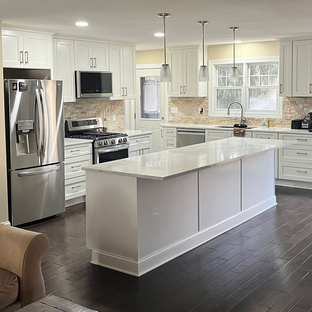 A kitchen with white cabinets , stainless steel appliances , and a large island.