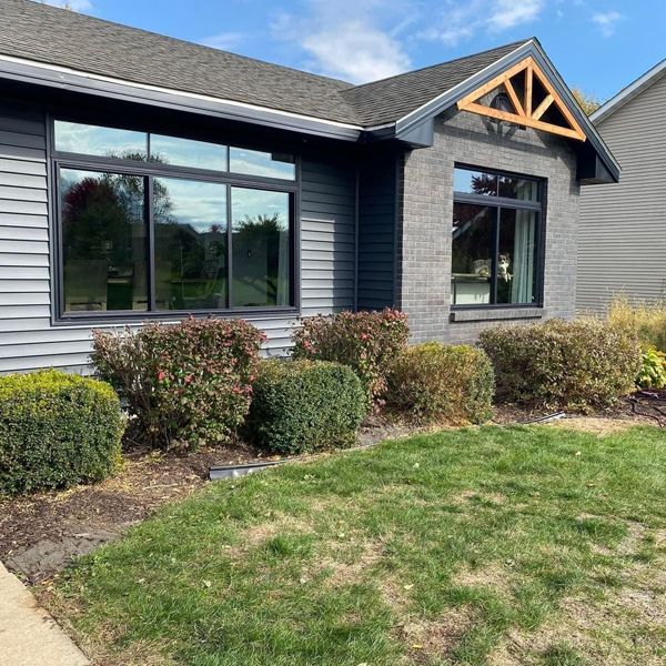 A house with a lot of windows and bushes in front of it.