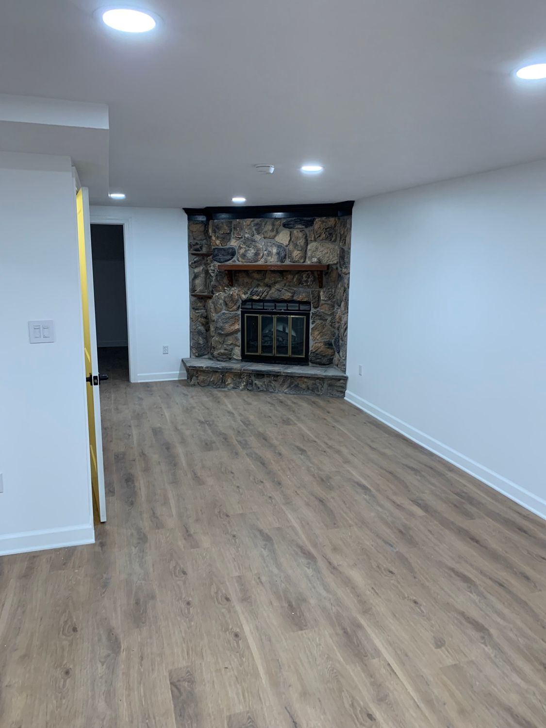 An empty living room with hardwood floors and a fireplace.