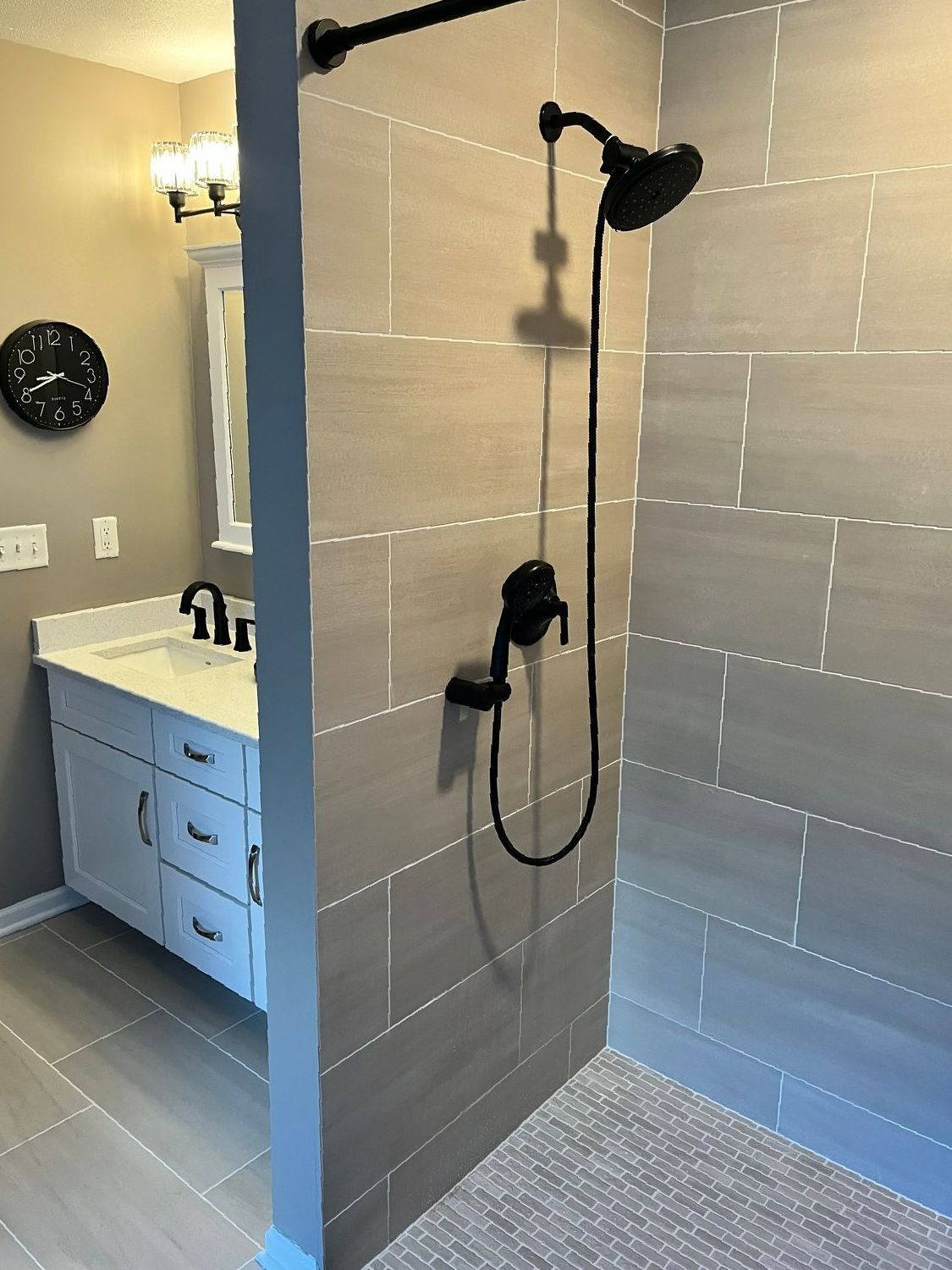 A bathroom with a walk in shower and a sink.