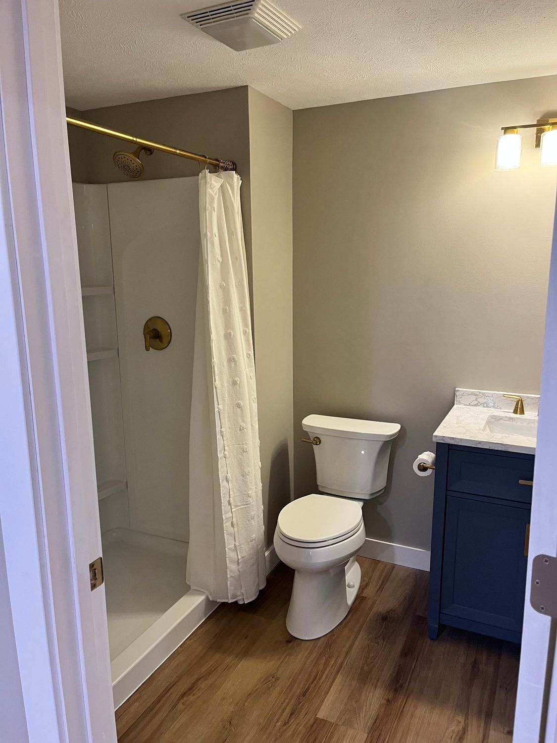 A bathroom with a toilet , sink and shower.
