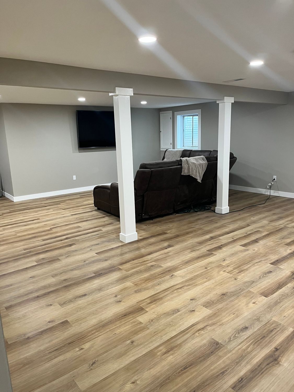 A living room in a basement with hardwood floors and a couch.