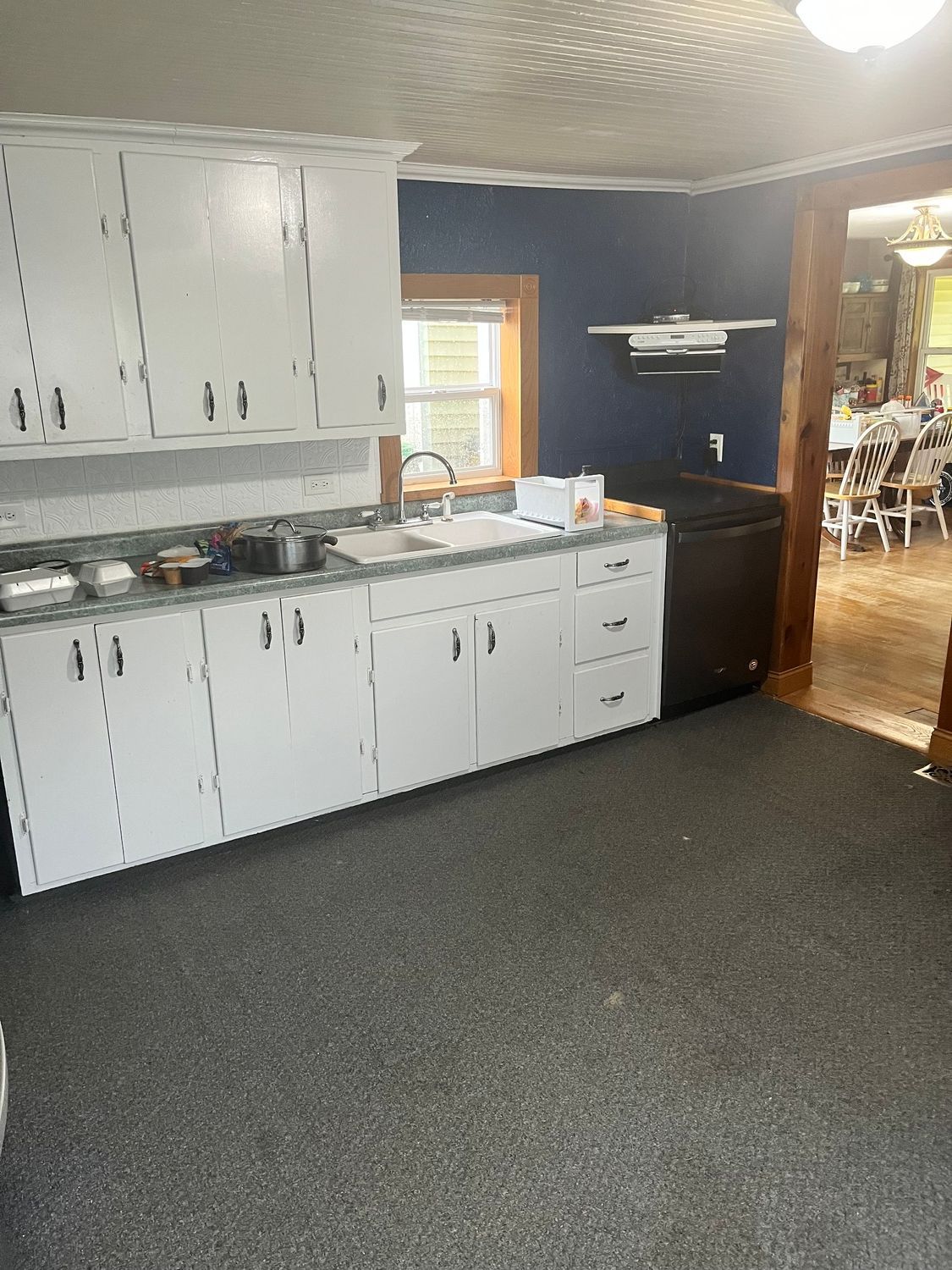 A kitchen with white cabinets , a sink , and a dishwasher.