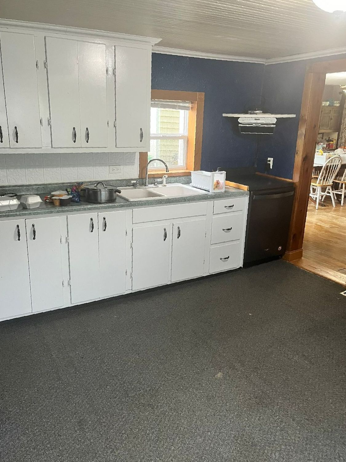 A kitchen with white cabinets , a sink , and a dishwasher.