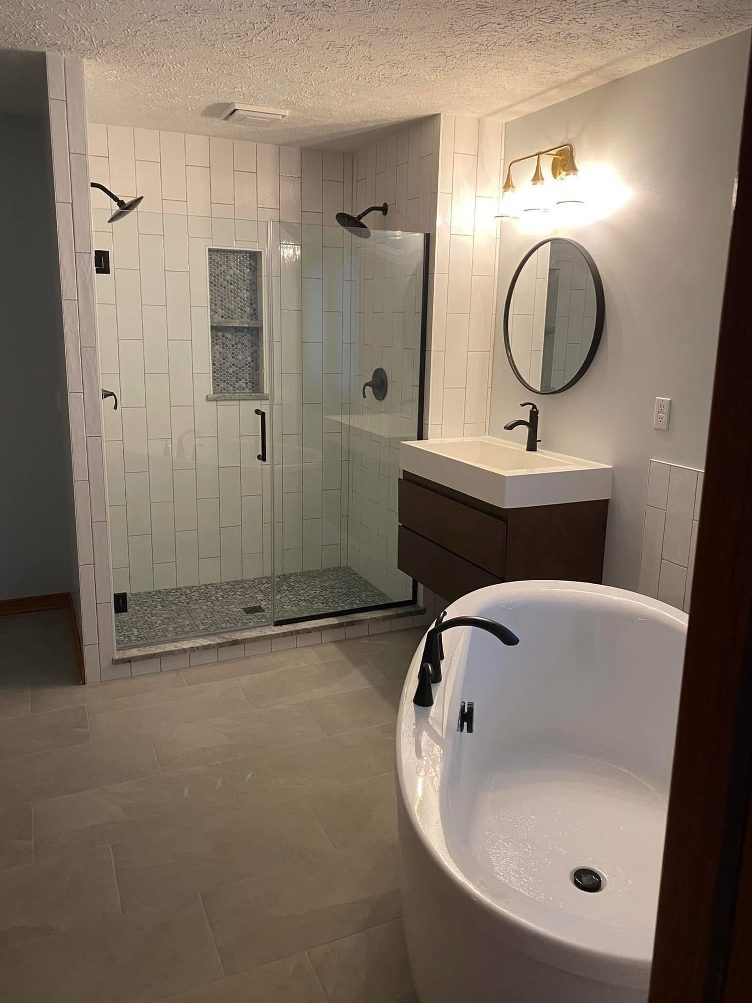 A bathroom with a tub , sink , shower and mirror.