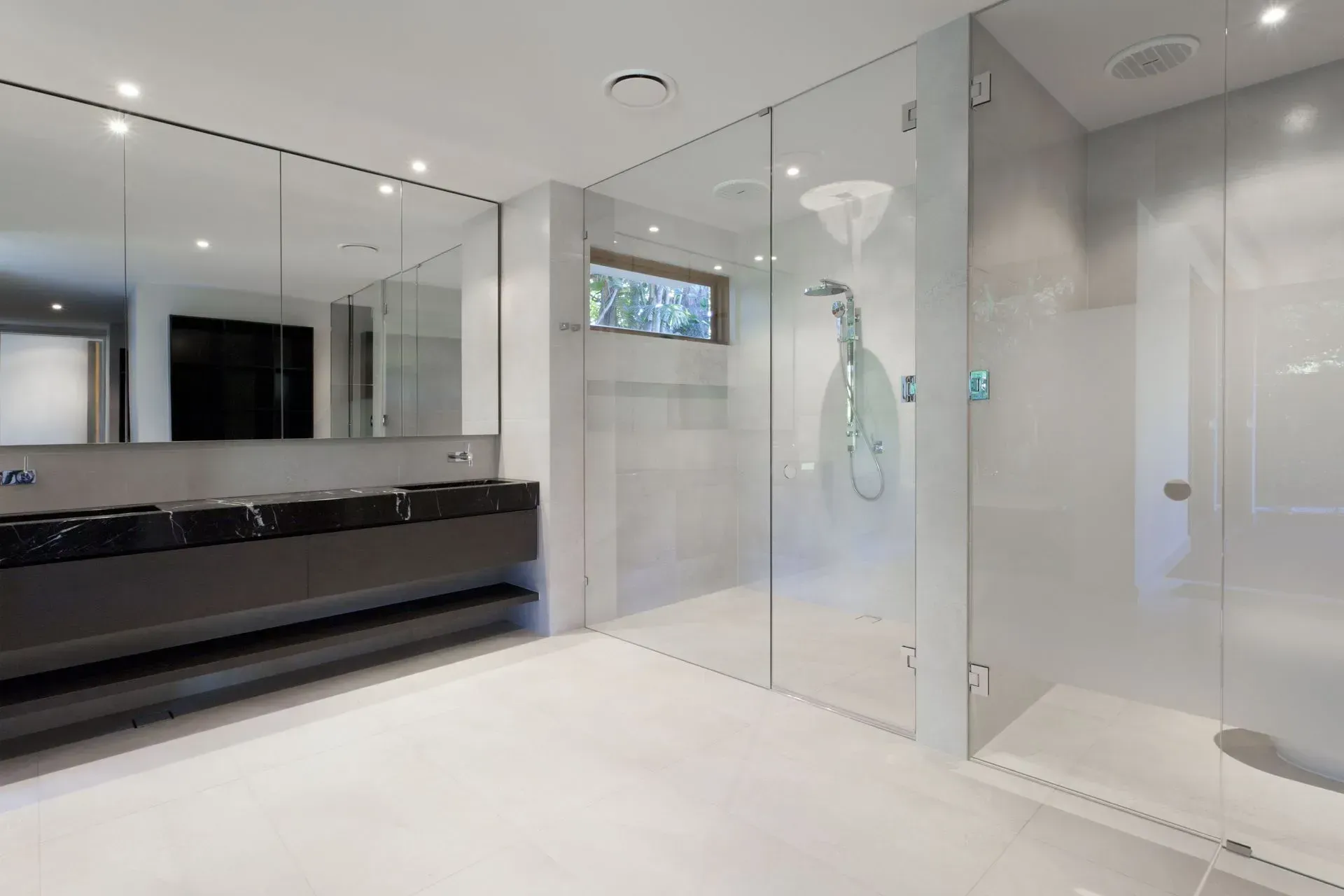 Modern bathroom with glass shower enclosure, white walls, and black vanity accents