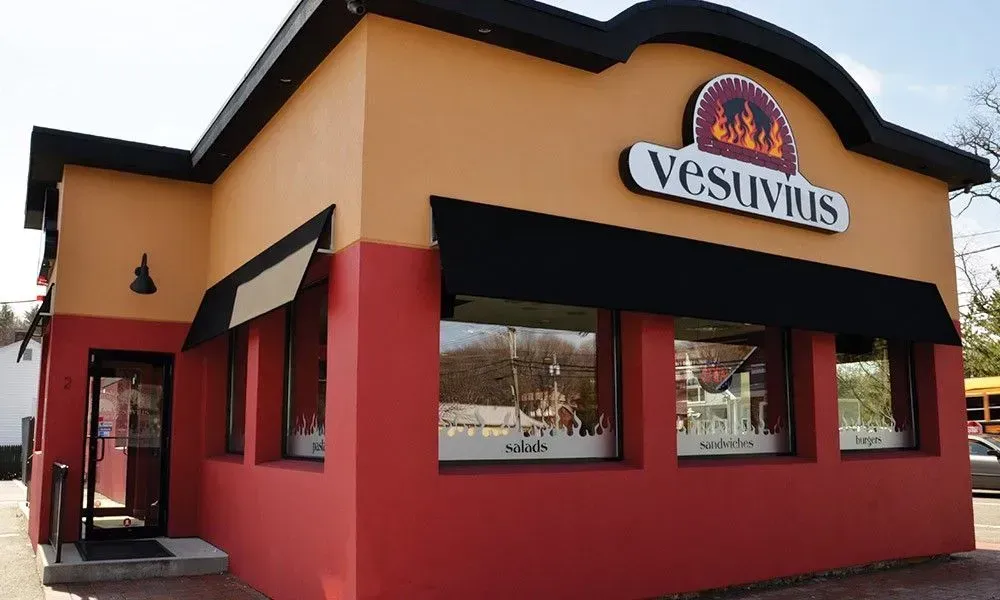 Vesuvio’s restaurant exterior with red walls, tan trim, and a black awning on a street corner