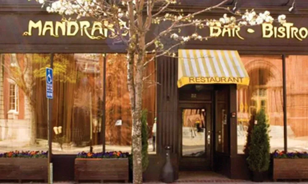 Exterior of Mandrake Bar Bistrot with a yellow awning and glass entrance in warm autumn light