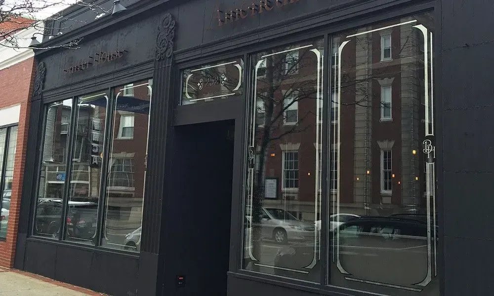 Black storefront with large windows and a central doorway on a city street