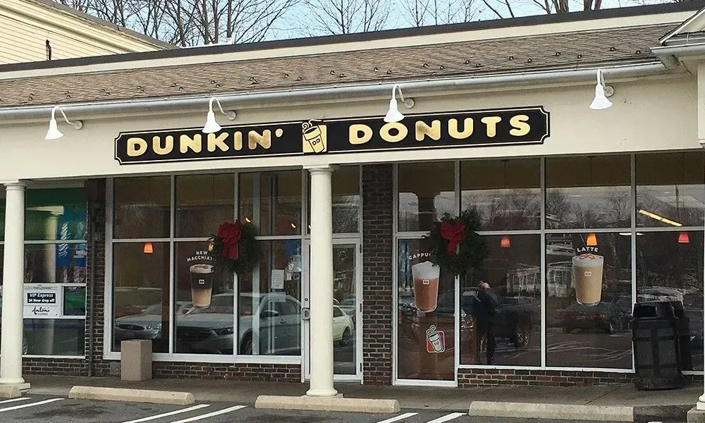 Dunkin’ Donuts storefront with large windows, white columns, and holiday wreath decorations