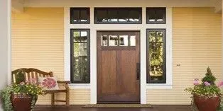 Front porch with a wooden door, windows, benches, and potted flowers on both sides