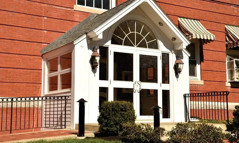 White front entrance with glass doors and a small awning on a red brick building