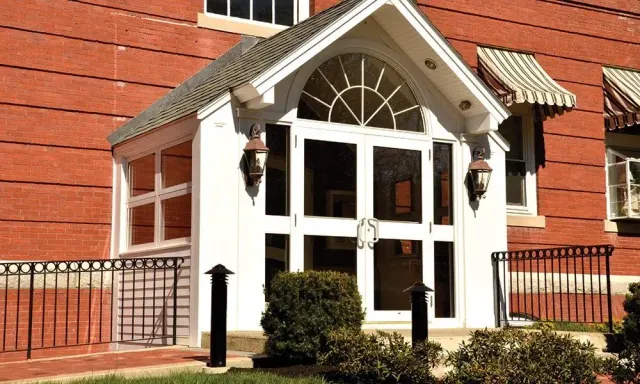 White entrance porch with glass doors and arched window on a red brick building